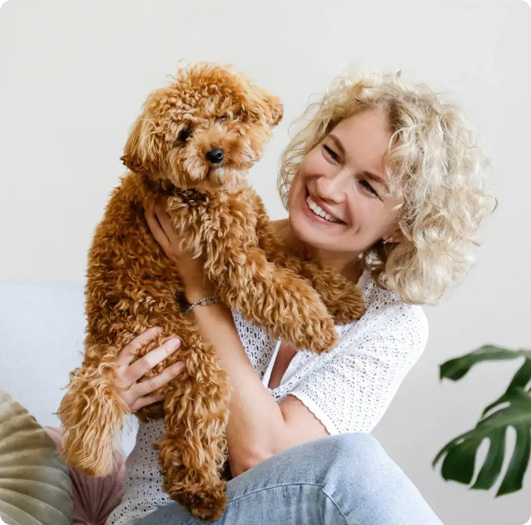 Woman holding a curly-haired brown dog.