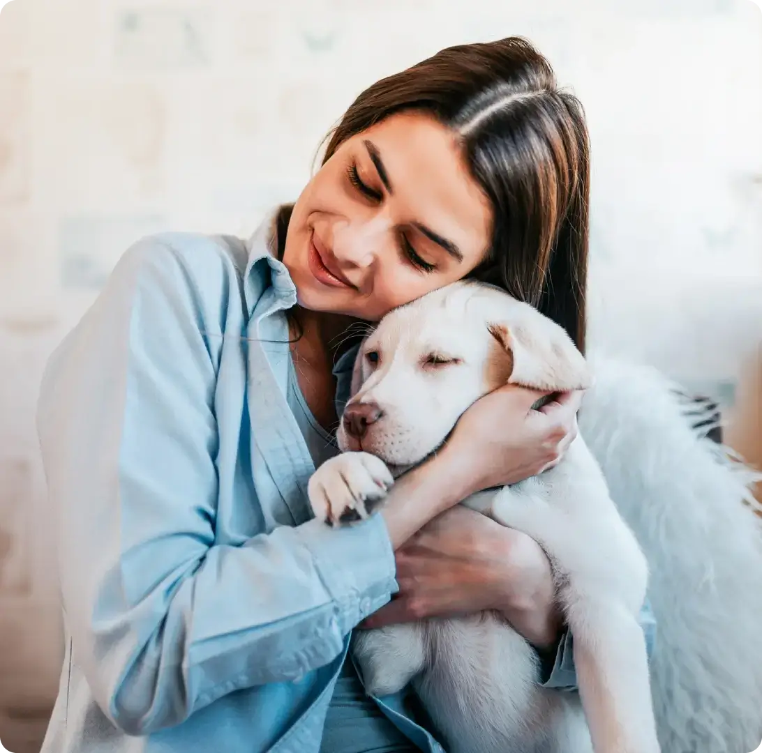 Woman hugging a sleepy Labrador puppy.